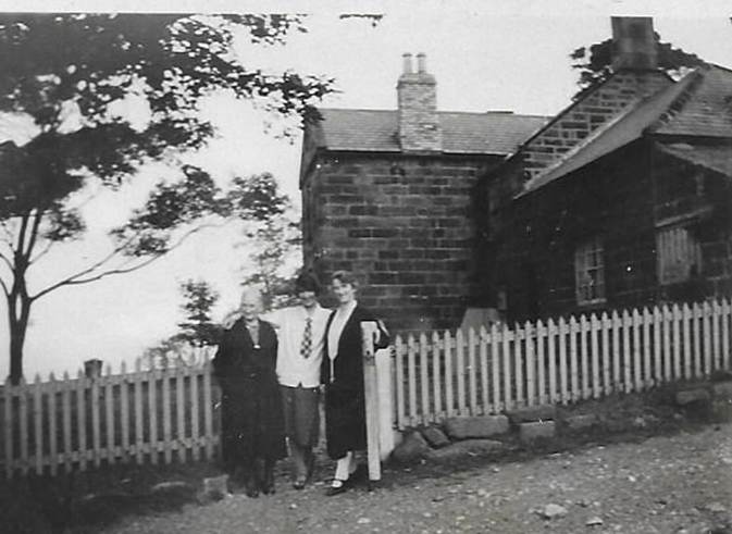 A black and white photo of a person walking by a fence
Description automatically generated